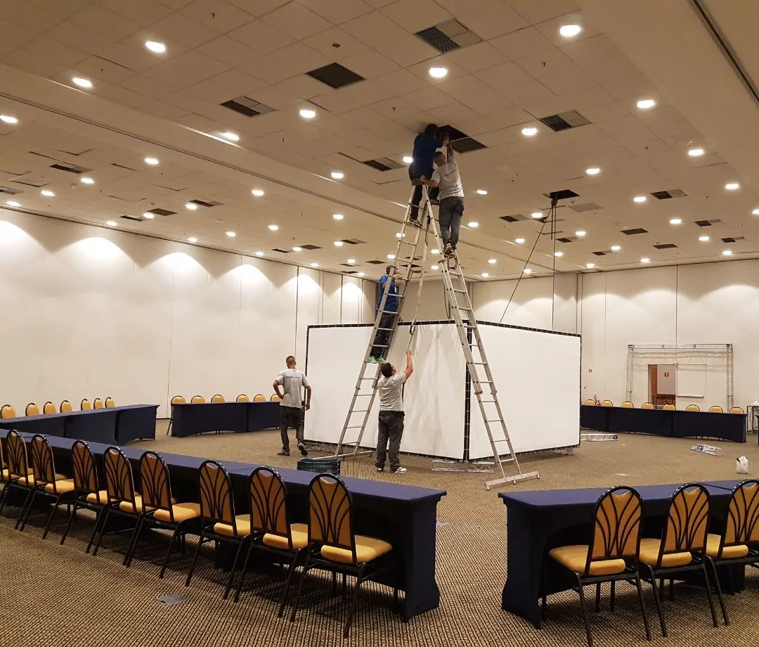 Técnicos montando estrutura em salão com mesas